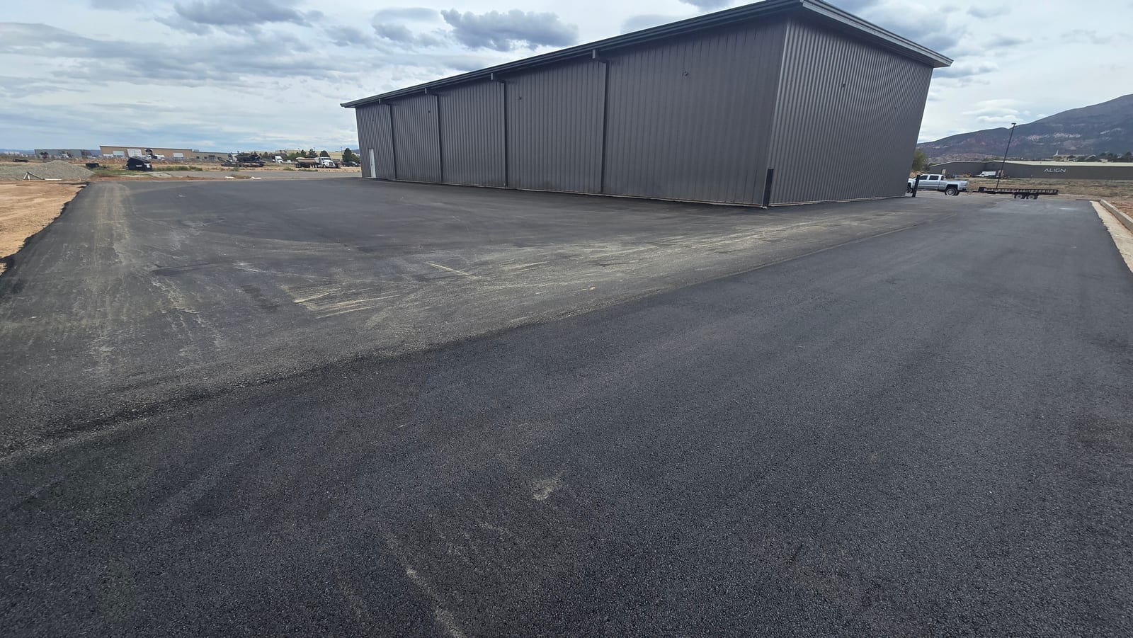 Freshly paved access road and equipment apron in Apple Valley, Utah — cut, graded, and base-prepped by Roxor South ahead of the asphalt crew